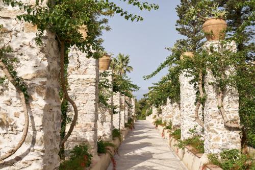 a stone wall with potted trees and a pathway at San Domenico Palace, Taormina, A Four Seasons Hotel in Taormina