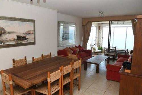 sala de estar con mesa de madera y sofá en Olas Marbella, Maitencillo. 4D+3B Vista Panorámica +Full Servicios, en Valparaíso