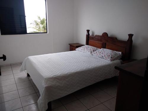 1 dormitorio con cama blanca y cabecero de madera en WI-FI 600MEGA 8 pessoas CENTRO da cidade frente mar 3quartos 2 carros, en Mongaguá