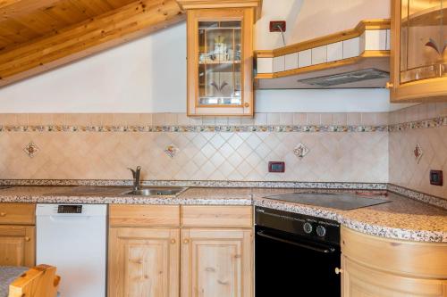 a kitchen with wooden cabinets and a sink at Casa Titol Ami Stella in Pozza di Fassa
