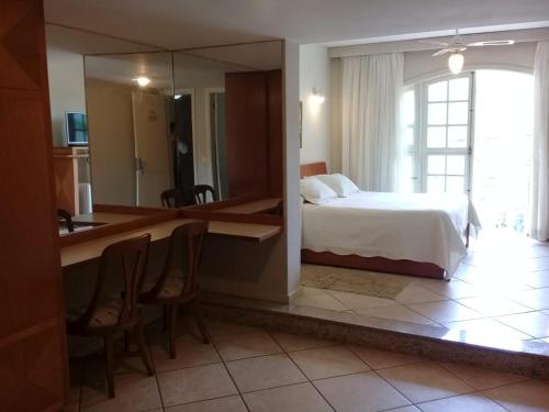 a bedroom with a bed and a desk with chairs at Hotel Dominguez Master in Nova Friburgo