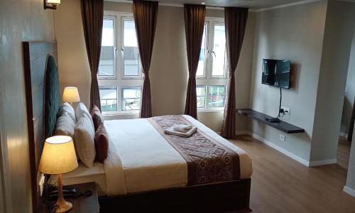 a bedroom with a bed and two windows and a television at HOTEL CLIFFTON ROYALS in Darjeeling