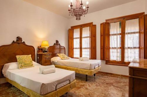 1 Schlafzimmer mit 2 Betten und einem Kronleuchter in der Unterkunft Santa Cruz Refinadores Suite by Valcambre in Sevilla