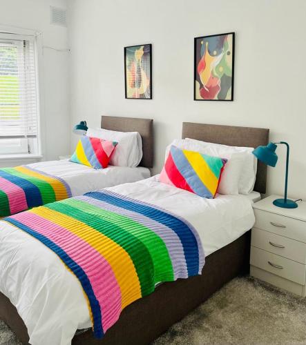 two beds with colorful blankets in a bedroom at Clyde 52 in Glasgow