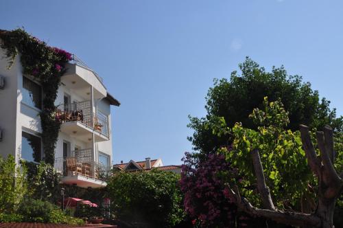 a building with flowering trees in front of it at Ece Hotel Sovalye Island in Fethiye
