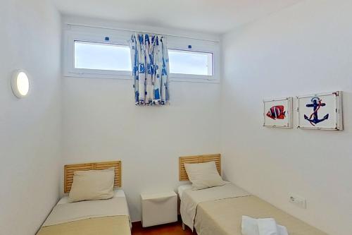 duas camas num quarto com duas janelas em Apartamento Binibeca Nou Cami de Cavalls em Binibeca