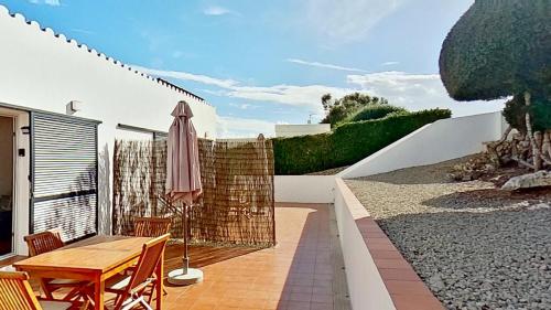 a patio with a wooden table and an umbrella at Apartamento Binibeca Nou Cami de Cavalls in Binibeca