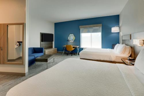 a hotel room with two beds and a blue wall at Holiday Inn Express Leland - Wilmington Area by IHG in Leland