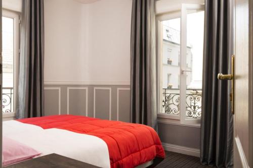 una camera da letto con un letto con una coperta rossa e una finestra di Bastille Hostel a Parigi