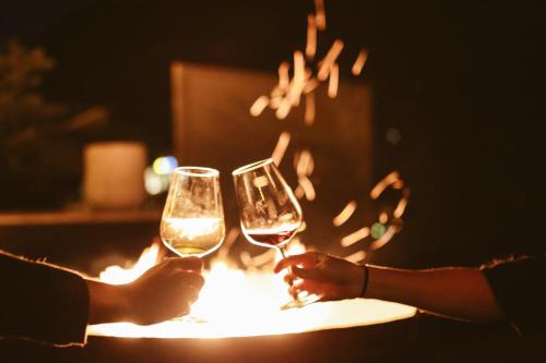 two people holding wine glasses in front of a fire at Design Hotel Miramonte in Bad Gastein