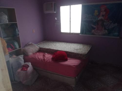 Habitación pequeña con cama roja y ventana en Casa Mobiliada en Manaus