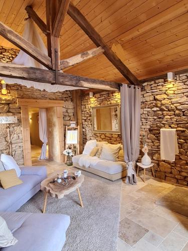 a living room with couches and a stone wall at Le Clos de la Tour in Sainte-Nathalène