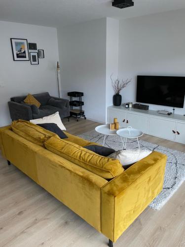 a large yellow couch in a living room at Holland 7 im Torrentblick brandnew family appartment in Leukerbad