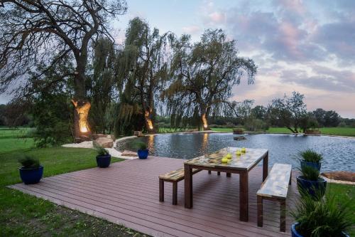 a wooden deck with a table and benches next to a pond at SCHLOSSRESIDENZ - Boutique Apartments & Hotel Suiten in Schloß Ricklingen