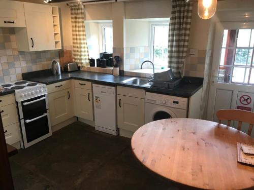 a kitchen with a table and a sink and a stove at Cherry Tree Cottage, Aysgarth in Leyburn