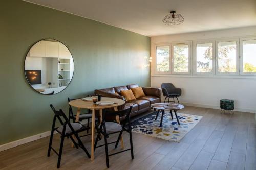 un salon avec un canapé, une table et un miroir dans l'établissement Le Sauge - Beauzelle, à Beauzelle