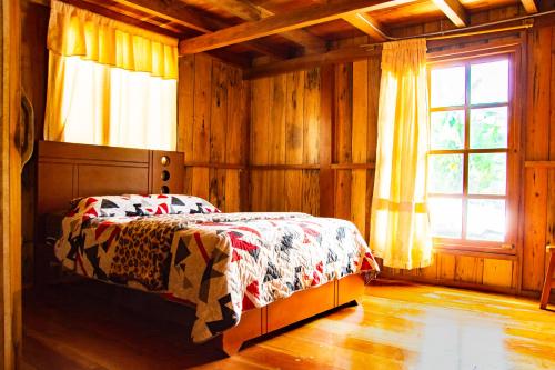 1 dormitorio con cama con edredón y ventana en RANA DE CRISTAL en Mindo