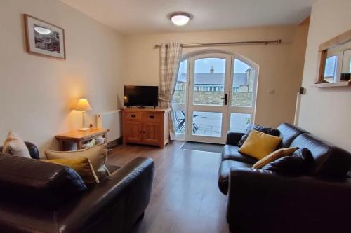 a living room with two leather couches and a television at Sandpiper Cottage in Alnham