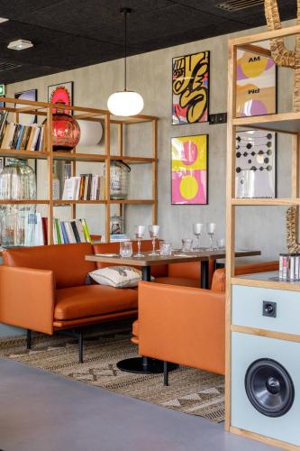 a room with a couch and a table and shelves at JOST Hôtel Bordeaux Centre Gare Saint Jean in Bordeaux