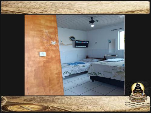 a room with two beds and a television in it at Pousada Piratas Di San Rocco in Maceió