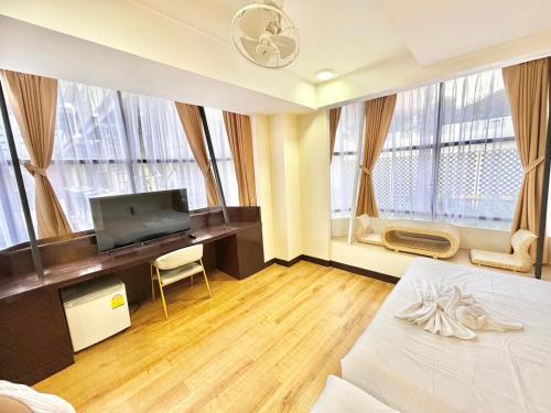 a bedroom with a bed and a desk with a television at ABC SO Hotel Bangkok in Bangkok