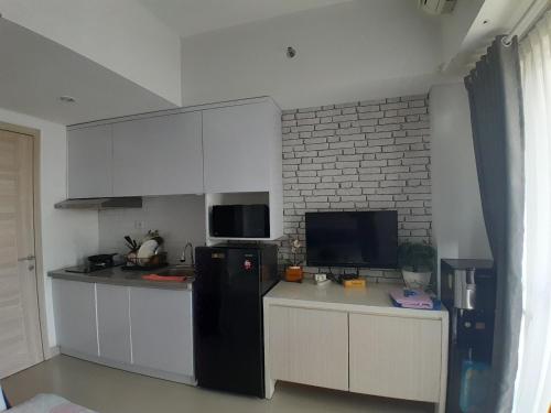 uma cozinha com um frigorífico preto e armários brancos em Niatmy em Kejayan