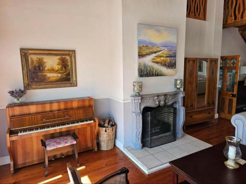 a living room with a piano and a fireplace at Valley View Eco Country Estate - Paradise in the Winelands in Villiersdorp