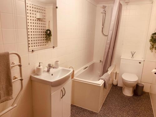 a bathroom with a sink and a tub and a toilet at 4 Swallowholm Cottage in Langthwaite