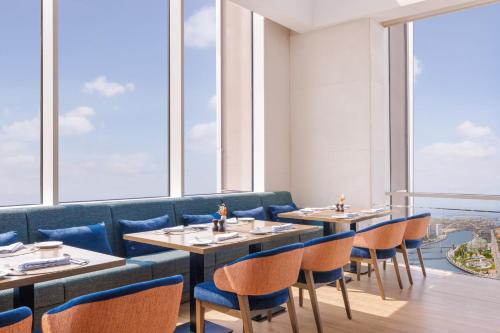 a restaurant with tables and chairs and large windows at Hilton Dubai Al Habtoor City in Dubai