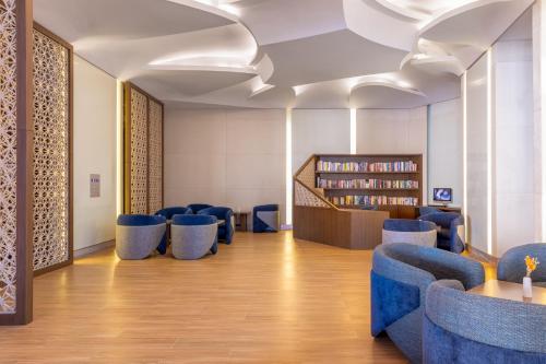 a library with blue chairs and a book shelf at Hilton Dubai Al Habtoor City in Dubai