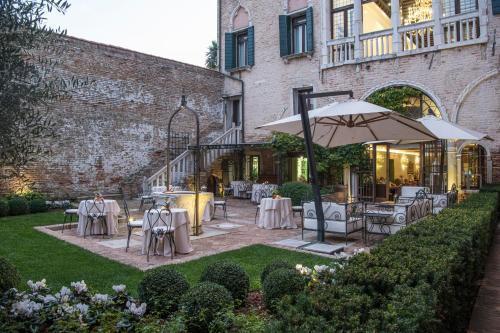 a patio with tables and chairs and an umbrella at Hotel Nani Mocenigo Palace in Venice