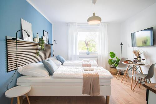 1 dormitorio con cama blanca y pared azul en HOMEFY STUDIO HEAVEN - SELF CHECK-in - PARKING LOT - ELEVATOR, en Essen