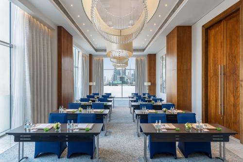 a dining room with blue tables and a chandelier at Hilton Dubai Al Habtoor City in Dubai
