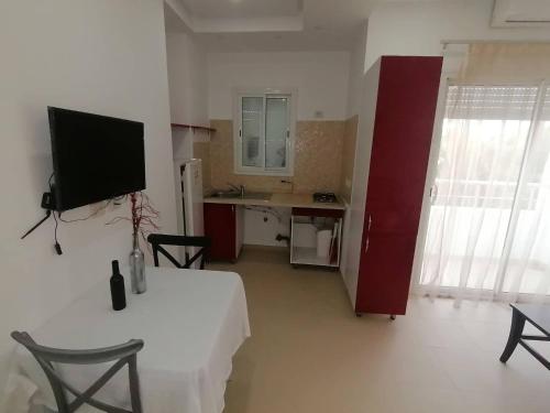 a living room with a table and a tv on the wall at maison d'hôte familiale للعائلات فقط in Sousse
