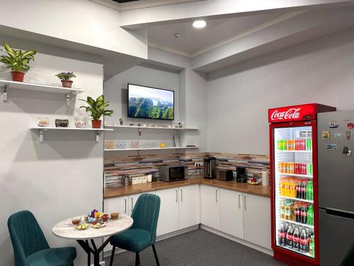 a kitchen with a table and a cocacola refrigerator at Stay Hostel in Bishkek