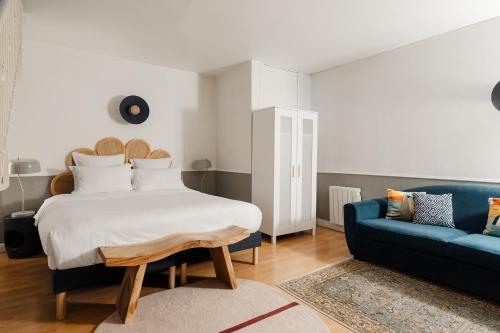 a bedroom with a bed and a blue couch at Edgar Suites Saint-Augustin - Naples in Paris