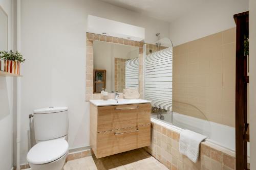 a bathroom with a toilet and a sink and a tub at Edgar Suites Saint-Augustin - Naples in Paris