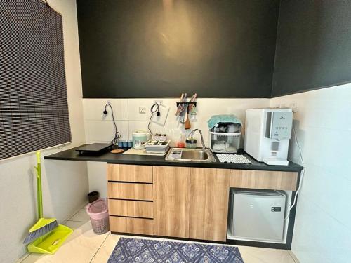 a small kitchen with a sink and a microwave at Manhattan Suites by NAJ in Penampang