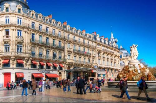 um grupo de pessoas andando em frente a um grande edifício em Joli Appart / Parking / CLIM / WIFI em Montpellier