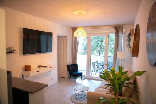 ein Wohnzimmer mit einem Sofa, einem Schreibtisch und einem TV in der Unterkunft Joli Appart / Parking / CLIM / WIFI in Montpellier