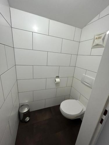 a white bathroom with a toilet and a trash can at Tennis- und Freizeitzentrum Neudörfl in Neudörfl