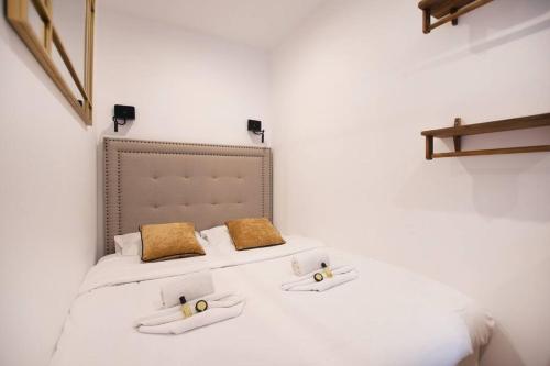 - un lit avec des draps blancs et des oreillers en or dans l'établissement Luxury Suite w/ Jacuzzi - Rex / Montorgueil, à Paris