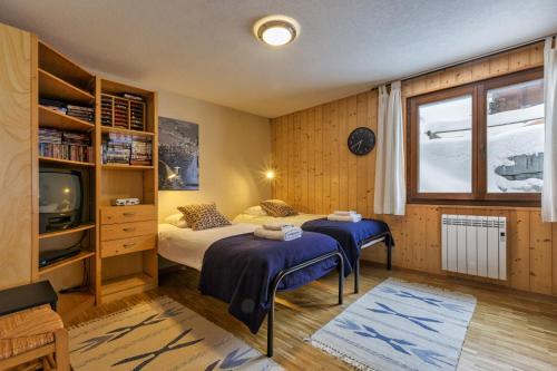 a bedroom with two beds and a tv in it at Chalet Les Jeunes - Swiss Ski Chalet with amazing views 8pax in Riddes
