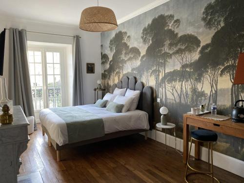 um quarto com uma cama com uma grande pintura na parede em Maison Prieuré 
