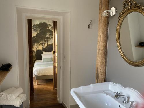 uma casa de banho com um lavatório, um espelho e uma cama em Maison Prieuré 