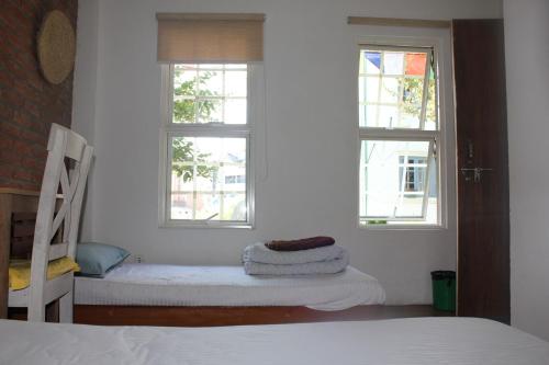 a bedroom with two windows and a bed and a chair at KAJI HOME in Pātan