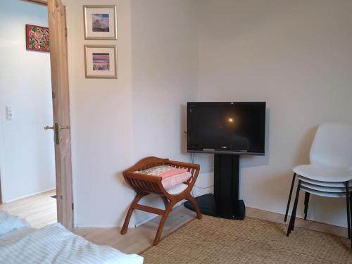 a room with a tv and a chair and a table at Flat, heart of Billund, 600m to Lego House, close to Legoland, Lalandia, Airport, in Billund