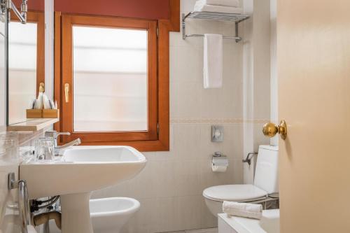 La salle de bains est pourvue d'un lavabo, de toilettes et d'une fenêtre. dans l'établissement Hotel Sant Jordi by ALEGRIA, à Andorre-la-Vieille