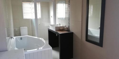 Baño blanco con lavabo y espejo en Durbanville Luxury Living Private Room, en Durbanville