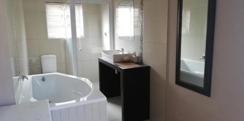 Un baño blanco con lavabo y espejo. en Durbanville Luxury Living Private Room, en Durbanville